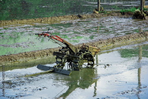 soiled and rusty tractor in paddy field  wet tractor in field