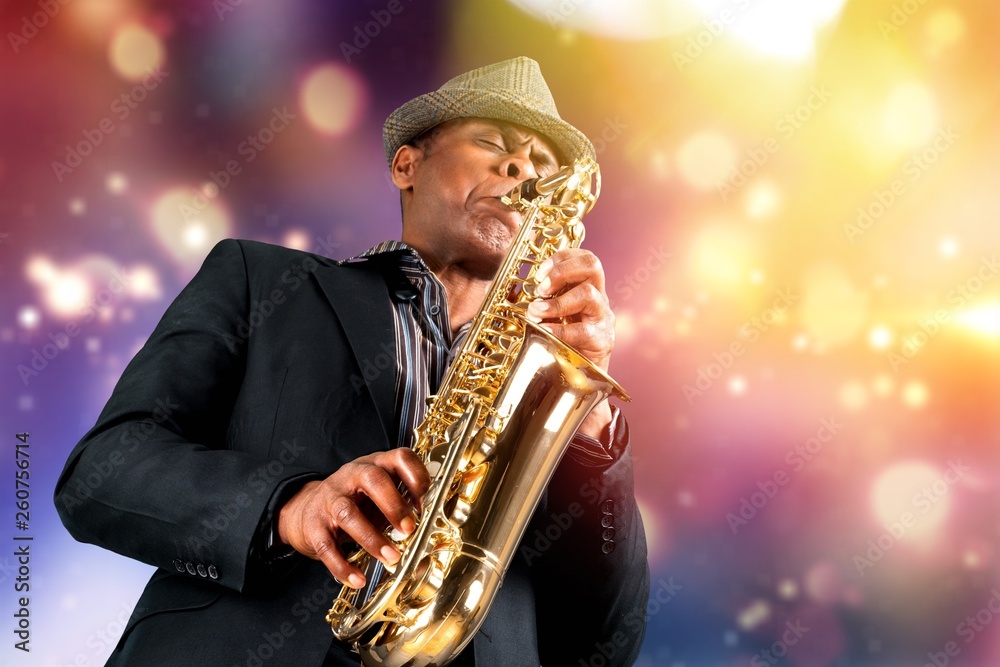 Obraz premium Close-up man playing on saxophone on blurred background