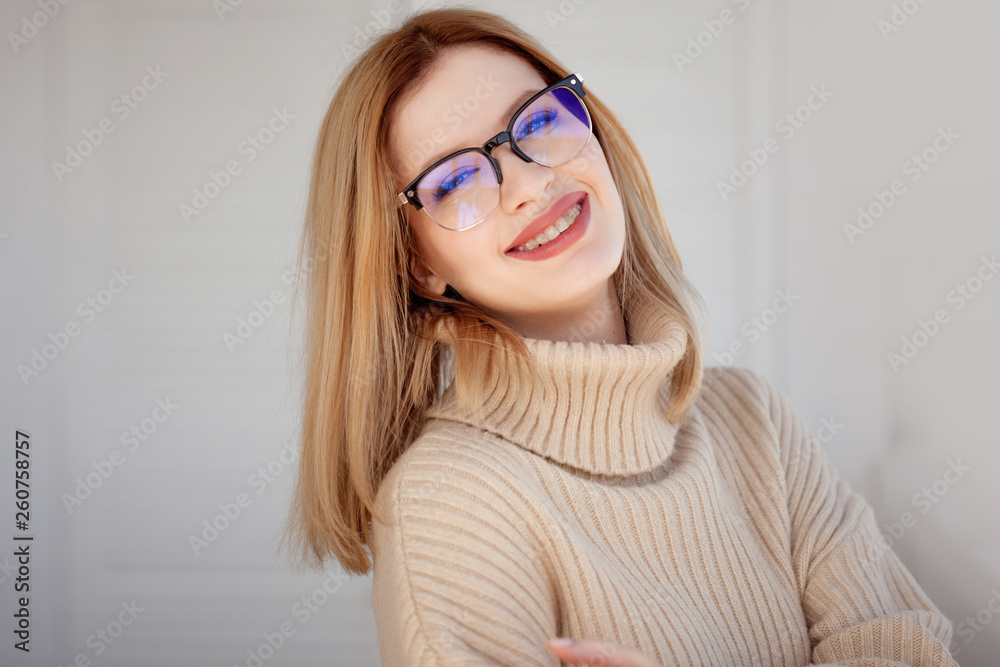 Young cute blonde with eyeglasses and a beige sweater. Stylish fashionable young woman. Young cute blonde with eyeglasses and a beige sweater. Stylish fashionable young woman.
