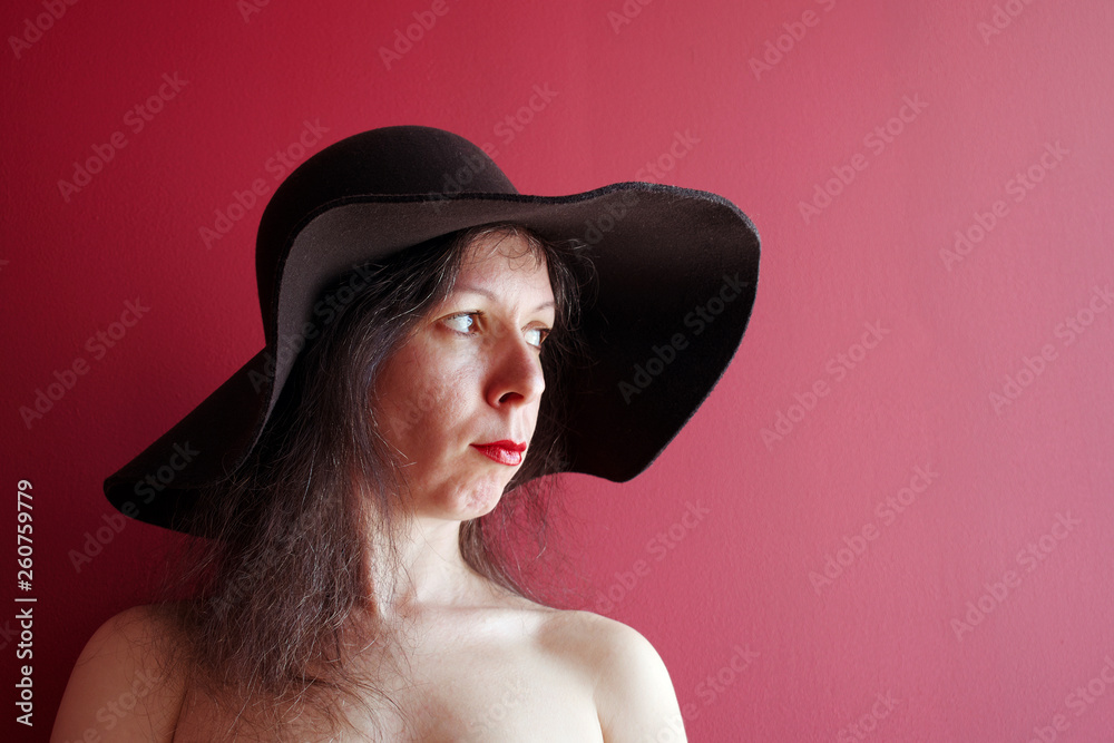 Portrait of offended young woman in black hat on red background Portrait of offended young woman in black hat on red background