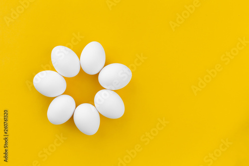White chicken eggs lie in the form of a flower on a yellow background. Healthy organic food and diet concept. Abstraction. Easter theme