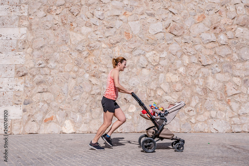 Woman, mother doing fitness pushing the baby stroller.