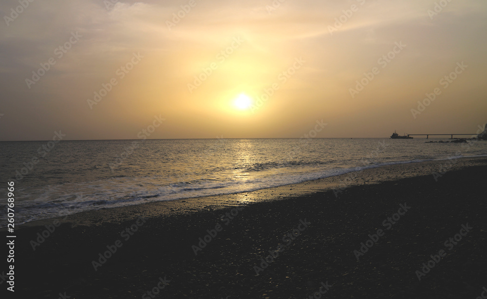 Dark shot of the sunset in the sea. The line of the beach with the waves of the sea at sunset. Horizontal, plenty of free space for text, the beauty of nature. The concept of nature