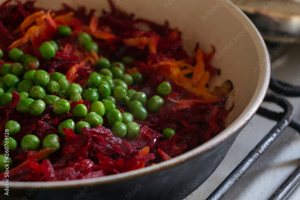 Green peas, beets and carrots stew in a frying pan Green peas, beets and carrots stew in a frying pan
