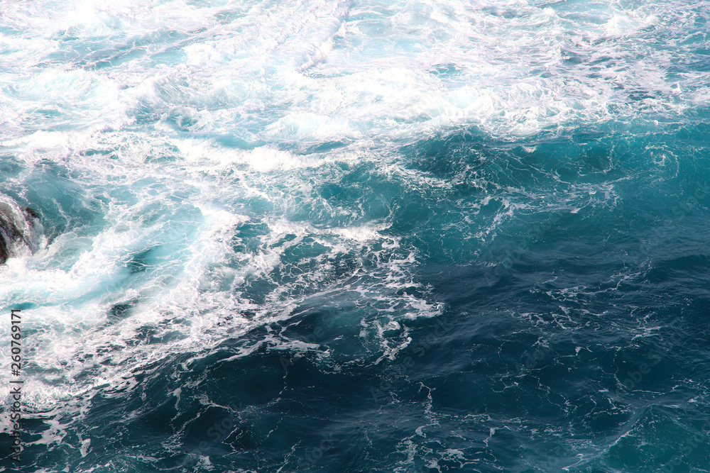 Blue gushing ocean. The waves of the ocean form a lot of white foam. Cropped shot, horizontal, a lot of free space for text, without people. Concept of nature and travel.