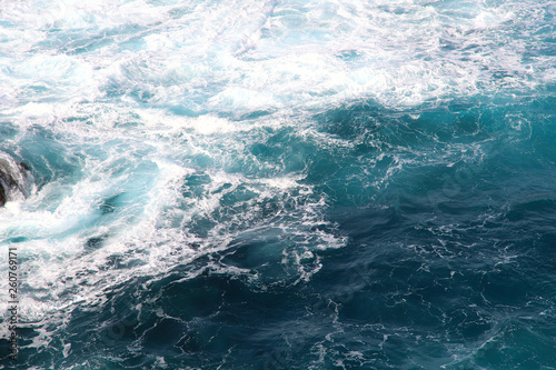 Blue gushing ocean. The waves of the ocean form a lot of white foam. Cropped shot, horizontal, a lot of free space for text, without people. Concept of nature and travel.