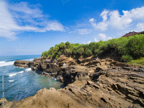 View of a cliff of rock on the coast of Bali. The sea waves hit the cliff, causing foam in the sea. The concept of world environmental day