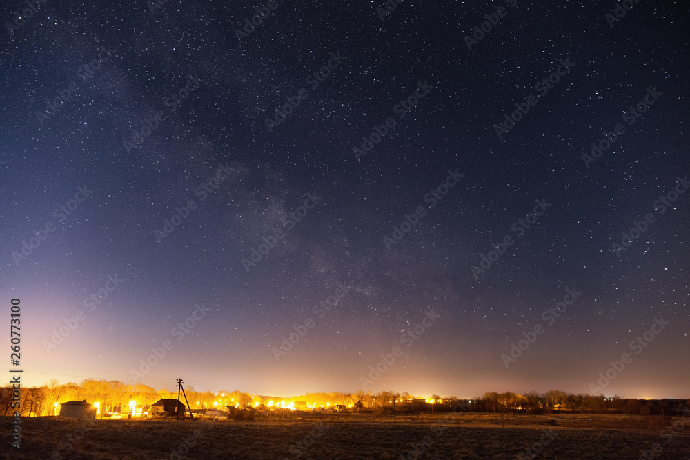 Milky Way over the illuminated small village Milky Way over the illuminated small village