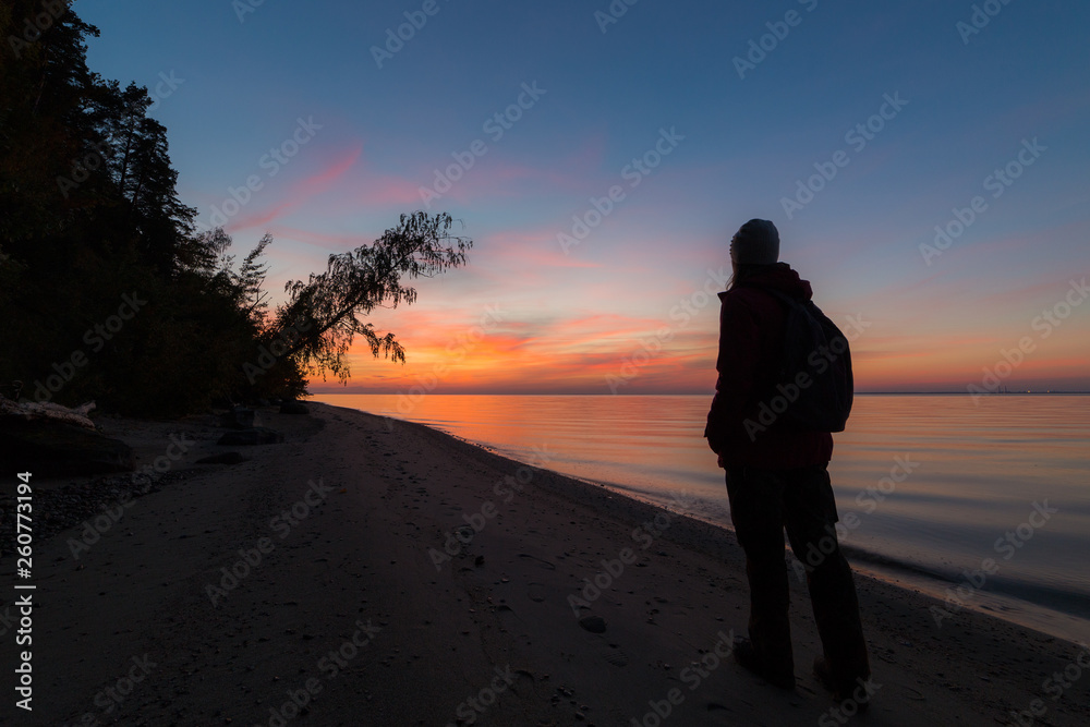 Silhouette of a young woman watching the sunset at the seashore