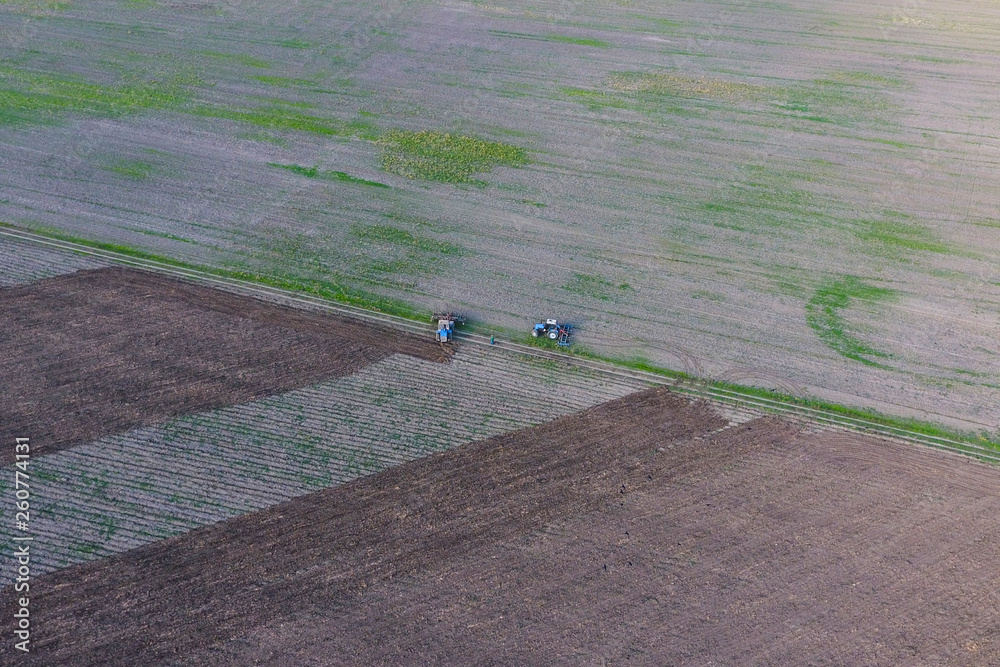 Obraz premium Top view of the tractor that plows the field. disking the soil. Soil cultivation after harvest