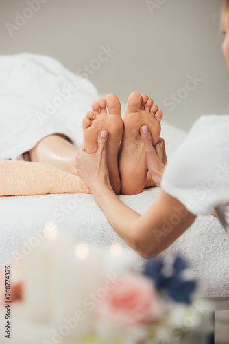 cropped view of masseur doing foot massage to adult woman in spa