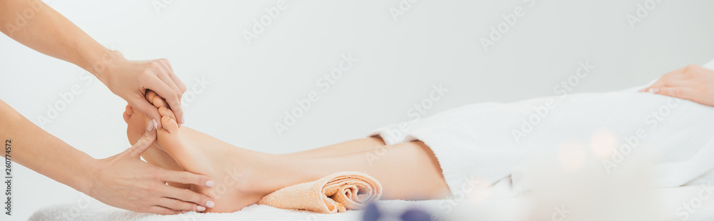Fototapeta premium panoramic shot of masseur doing foot massage to adult woman in spa