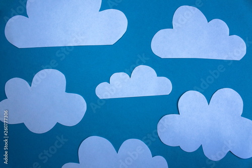 Cut out of paper clouds lie on a blue background