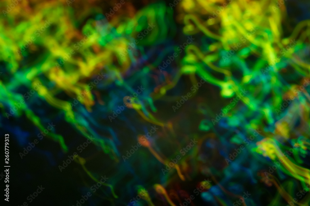 Blurred neon lights in motion. Thin curved multicolor lines on dark background. Lens flare effect. Blurred neon lights in motion. Thin curved multicolor lines on dark background. Lens flare effect.