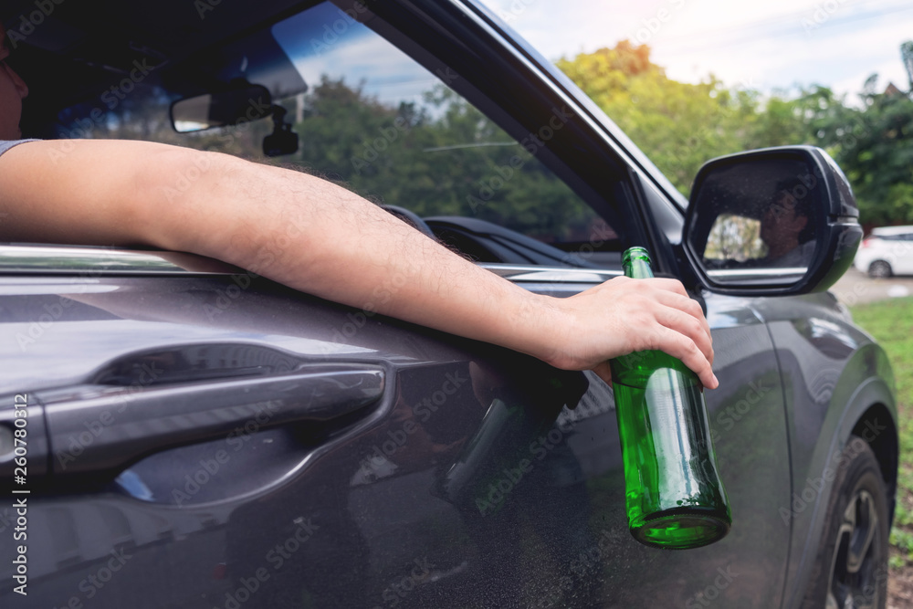 Don't Drink for Drive concept, Young Drunk man drinking bottle of beer or alcohol during driving the car dangerously Don't Drink for Drive concept, Young Drunk man drinking bottle of beer or alcohol during driving the car dangerously