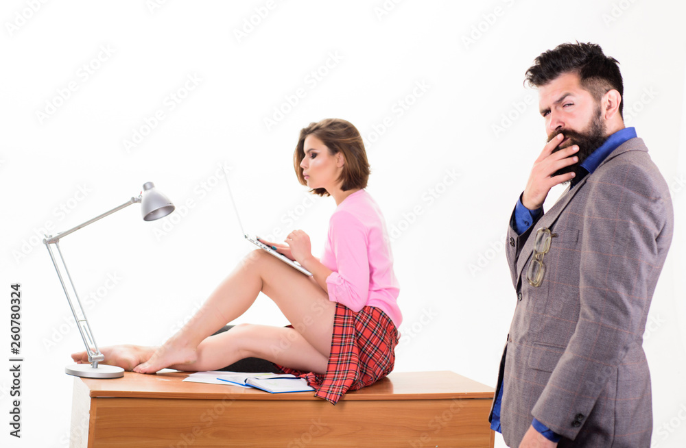Thinking on serious problem. Serious man touching beard by hand and sexy  woman sitting on desktop. Businessman with serious face while sexi  secretary using laptop. Hipster having serious look foto de Stock