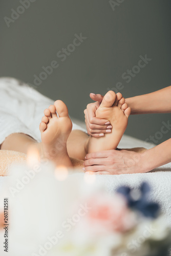partial view of masseur doing foot massage to adult woman in spa
