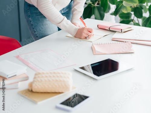 Social network business. Internet marketing. SMM woman at workplace making notes in schedule. Tablet and smartphone.