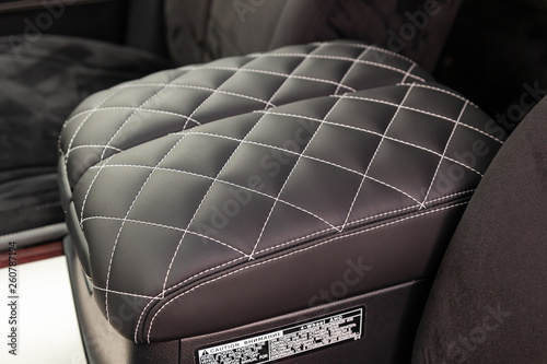 Interior of a luxury car with leather interior overtightened stitching in the form of a diamond of white thread at central armrest in a vehicle repair shop. Design atelier auto service. photo