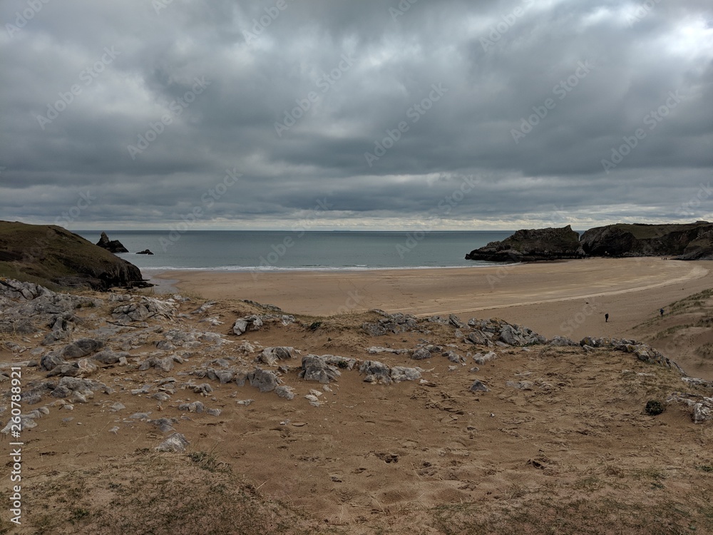 Stormy, Cloudy Grey Welsh Coastline with Sandy Beach & Rocksand Waves