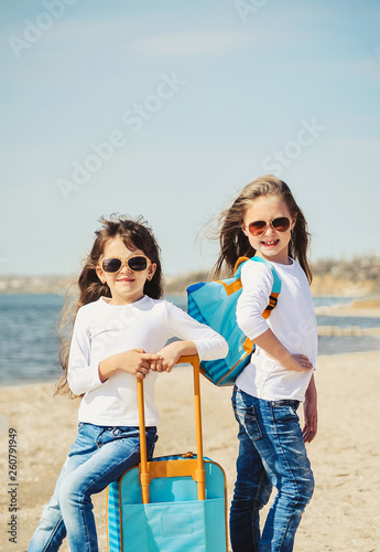 Cute little girls with suitecases on the beach are ready to travel. Summertime  photo