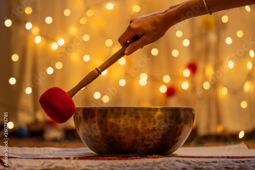 Handmade hammered Tibetan singing bowl on yellow bokeh background, alternative medicine concept photo