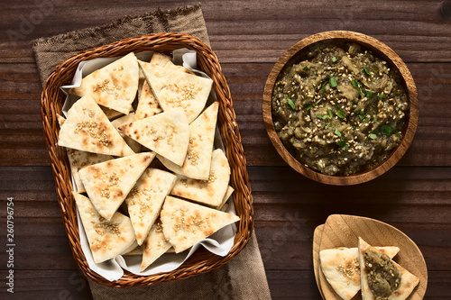 Homemade sesame pita chips with roasted eggplant dip or spread, baba ganoush in the Mediterranean cuisine on the side, photographed overhead with natural light photo