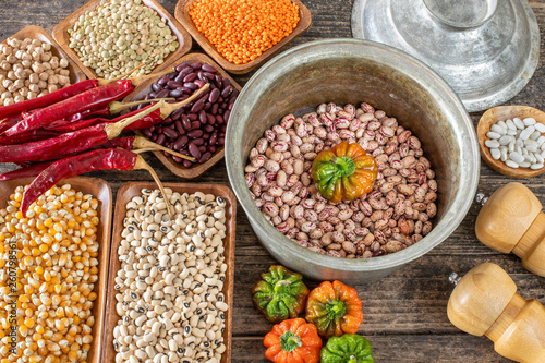 Legumes in the bowl and in the copper cookware on the rustic wooden table