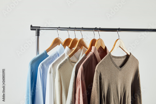 Straight rack, wooden hangers and male clothes isolated on grey