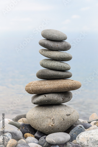 Pyramid of sea stones on pebbles of the sea shore. Seascape. The concept of balance and spirituality.