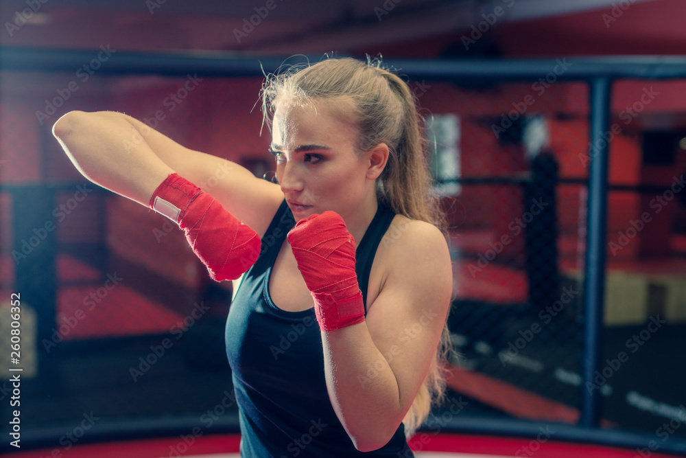 Boxing , wrestling , and MMA duel . Young strong girl kickboxer fighter  stands in a defensive or attacking