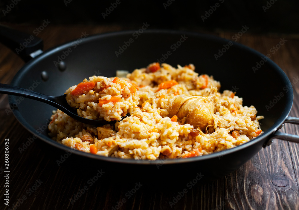Traditional homemade Uzbek pilaf or plov in iron frying pan. Uzbek cuisine. Close Up. Selective Focus. Traditional homemade Uzbek pilaf or plov in iron frying pan. Uzbek cuisine. Close Up. Selective Focus.