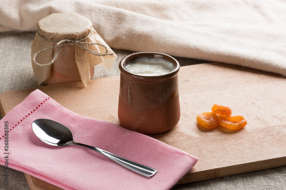 White homemade yogurt in a clay jar with dried apricot White homemade yogurt in a clay jar with dried apricot