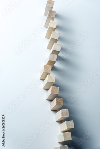 A long curved line of wooden cubes  as a symbol of a queue  competition for a position or team  on a uneven white background. Vertical frame
