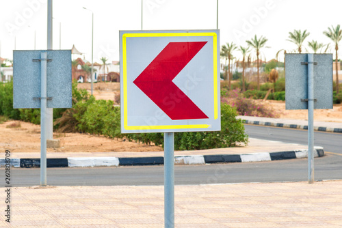 Square white road sign with a red arrow turned to the left. Horizontal frame