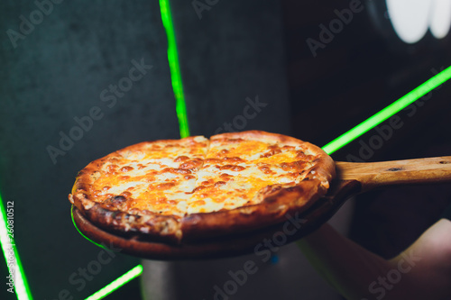 Steaming hot tasty margarita Italian pizza fresh from the pizza oven in a pizzeria served on a long handled wooden board with copyspace behind. photo