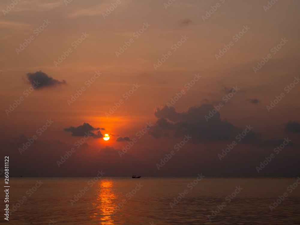 Silhouette of a boat on the background of the setting sun with clouds. Koh Phangan Thailand