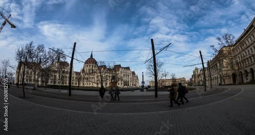 BUDAPEST, HUNGARY - JANUARY 17, 2019 : Yellow tram passes in front of the Gothic architecture of famous Hungarian Parliament building exterior view at winter time. Time lapse