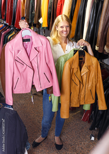  blonde choosing leather jacket on racks