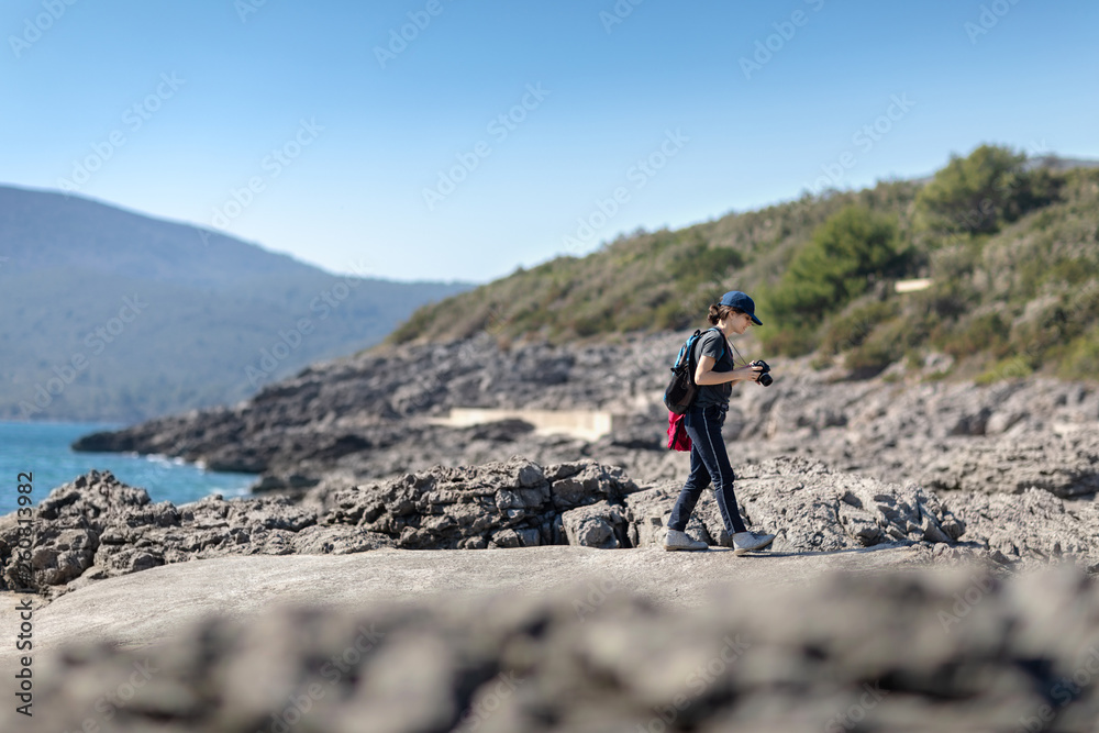 woman with backpack and camera walking near the sea