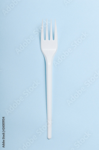 Plastic white disposable plug on a blue background. Concept plastic dishes  fast food  plastic pollution. Top view  flat lay.