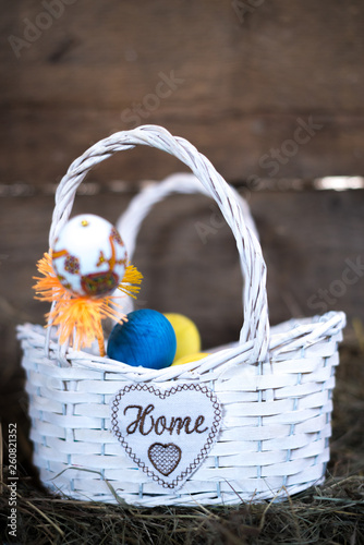 Easter eggs in a basket on a hay with a blurred background