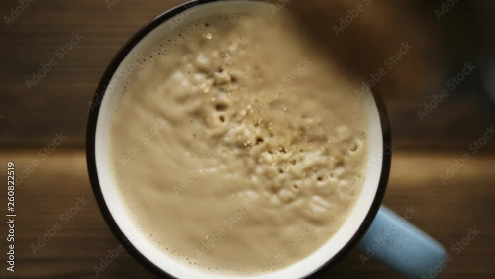 SLow motion shot of pour cane sugar from spoon into cup of coffee with milk SLow motion shot of pour cane sugar from spoon into cup of coffee with milk