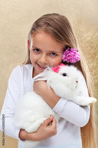 Happy little girl holding her cute white rabbit