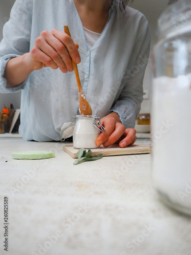 Canvas Print Caucasian woman making homemade vegan deodorant in a glass jar adhering to a zer