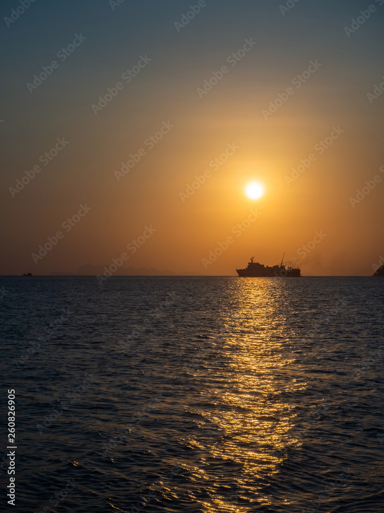 Silhouette of a ferry in the rays of the setting sun with clouds. Koh Phangan Thailand