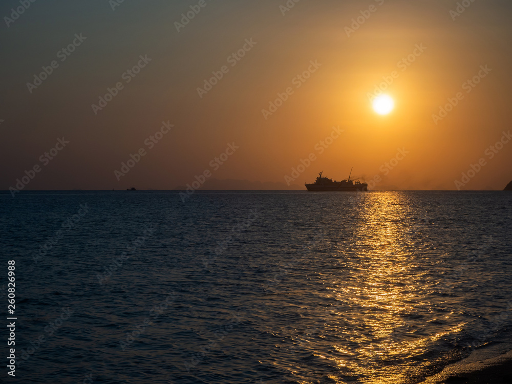 Silhouette of a ferry in the rays of the setting sun with clouds. Koh Phangan Thailand Silhouette of a ferry in the rays of the setting sun with clouds. Koh Phangan Thailand