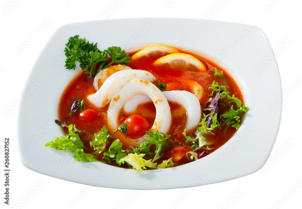 Spicy tomato soup with sea squids and greens served in a white bowl