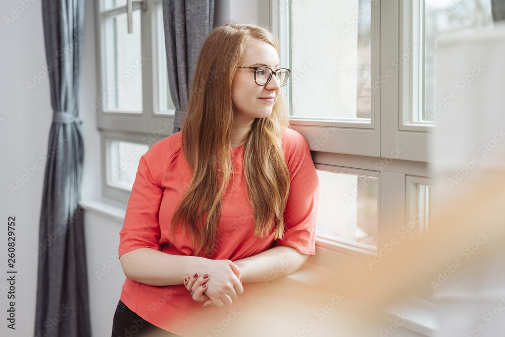 Young woman standing watching through a window Young woman standing watching through a window
