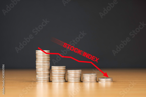 Decreasing of Stock Index. Stacked coins and red arrow show down trend Stock index. / Financial Concept